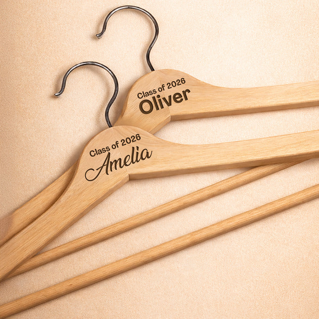 Three wooden hangers with engraved names on a beige background