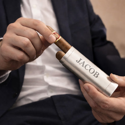 Person holding a silver Jacob cigar case with two cigars.
