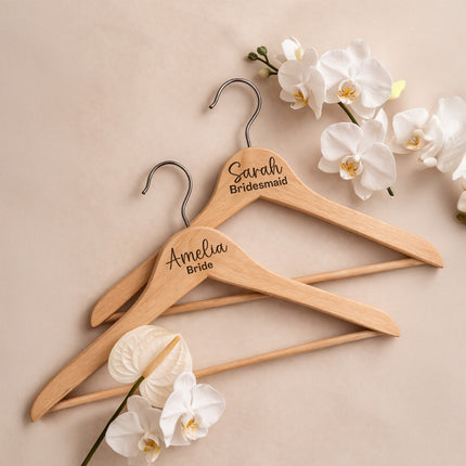 Three wooden hangers with personalized names on a beige background with white flowers.