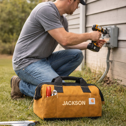 Man using a power drill with a Jackson tool bag on the grass.