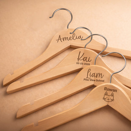 Set of wooden hangers with engraved names on a beige background