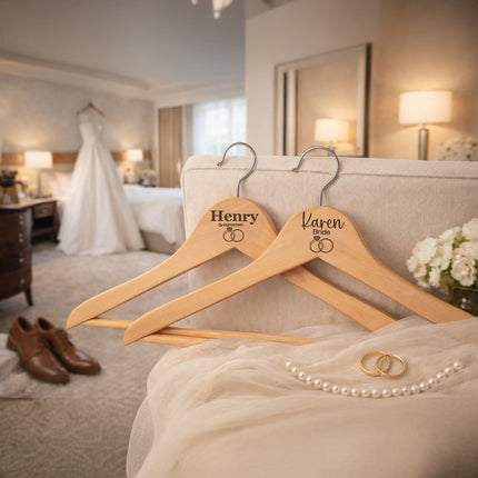Two wooden hangers with 'Henry' and 'Karen' engraved on them, placed on a bed in a bedroom setting.