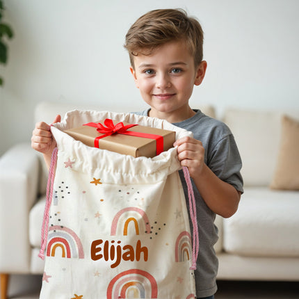 Child holding a gift bag with a name on it, standing in a living room.