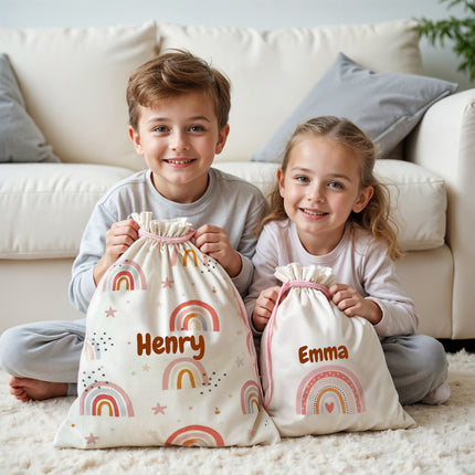 Two children holding personalized drawstring bags with rainbow patterns and names 'Henry' and 'Emma'.