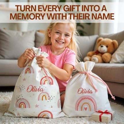 Child holding personalized gift bags with rainbow patterns and 'Olivia' text, sitting on a carpeted floor.