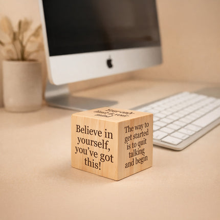 Wooden block with motivational quote on a desk with computer and keyboard