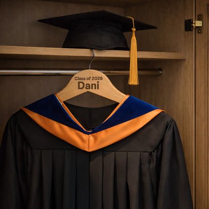 Graduation gown with cap on a hanger in a wooden closet.