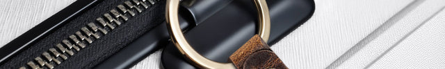 Brown leather keychain with engraved design attached to a black zipper on a white background.