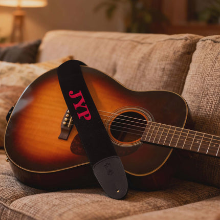Acoustic guitar with a strap on a couch