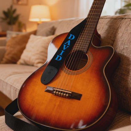 Acoustic guitar with a strap labeled 'DAVID' on a couch in a cozy living room.