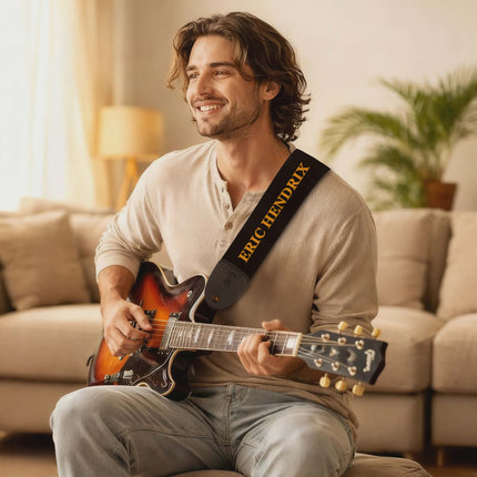 Man playing a guitar with an 'Eric Clapton' strap in a living room setting