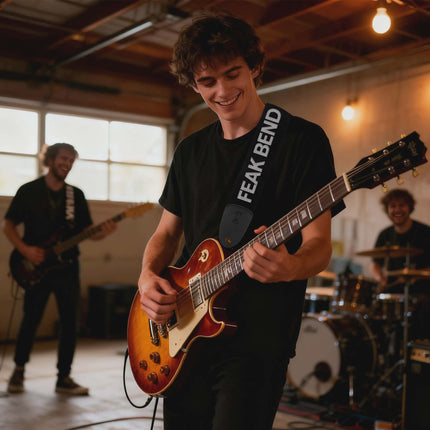 Person playing a guitar with 'Feak Bend' strap in a band setting