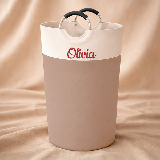 Beige laundry basket with 'Olivia' branding on a beige fabric background