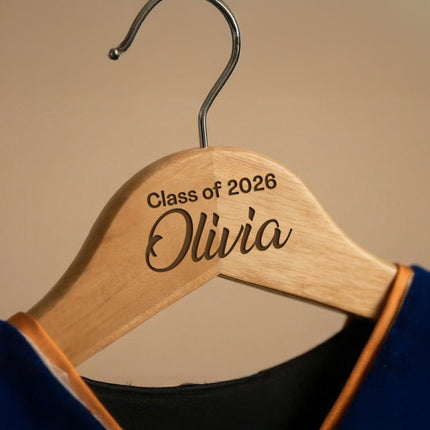 Wooden hanger with 'Class of 2026 Olivia' engraving on a beige background