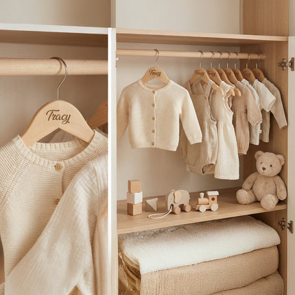 Children's wardrobe with baby clothes and toys in a neutral color scheme.
