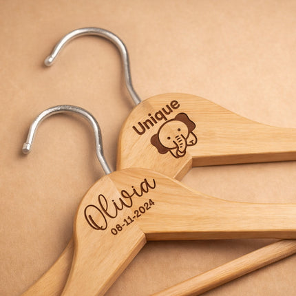 Wooden hangers with engraved names and dates on a beige background
