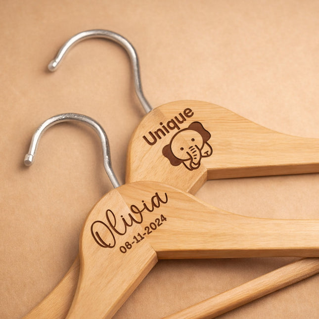Wooden hangers with engraved names and dates on a beige background