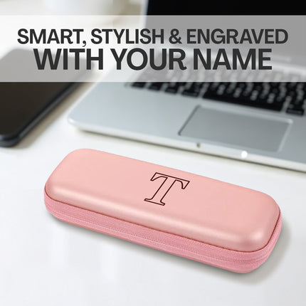 Pink glasses case with a monogram 'T' on a desk with a laptop and phone.