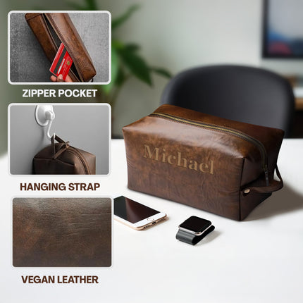 Brown leather toiletry bag with 'Michael' engraving, featuring zipper pocket, hanging strap, and vegan leather details.