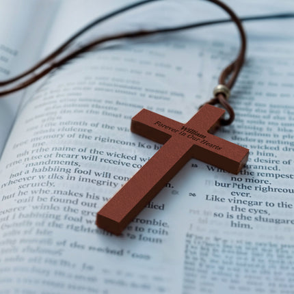 Wooden cross pendant on a leather cord over an open book