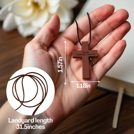 Hand holding a wooden cross pendant with measurements and brand logo.